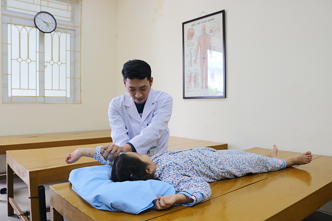 Bé 6 tuổi bị đột quỵ Bác sĩ tập các bài phục hồi chức năng cho cháu bé. Ảnh: Nguyễn Tuyết