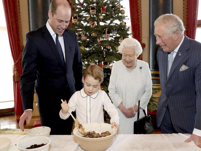 Harry và Meghan buồn bã khi bị loại khỏi các ảnh Giáng sinh Hoàng gia Một bức ảnh cho thấy Nữ hoàng Elizabeth, Thái tử Charles, Hoàng tử William và Hoàng tử George đang làm bánh pudding Giáng sinh - Ảnh: AP/ Buckingham Palace