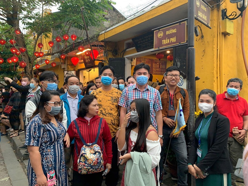 Du khách tham quan phố cổ Hội An được phát khẩu trang y tế miễn phí Một đoàn khách được phát khẩu trang y tế miễn phí sau khi mua vé. Ảnh: T.B