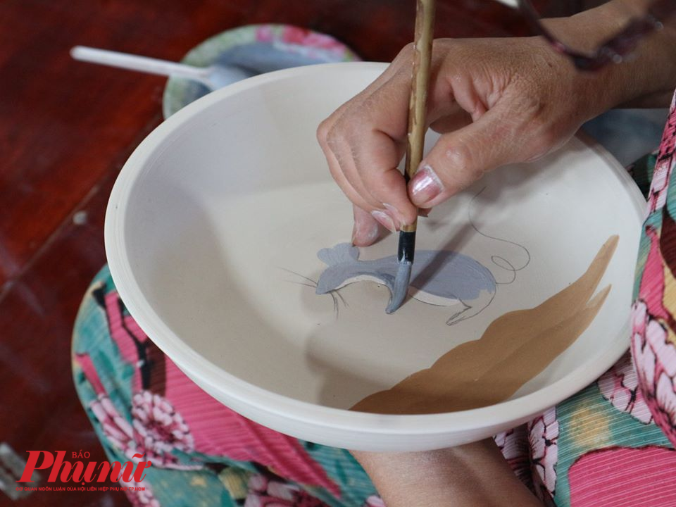 Nghệ nhân gốm thực hiện công đoạn chấm men vẽ hoa văn.
