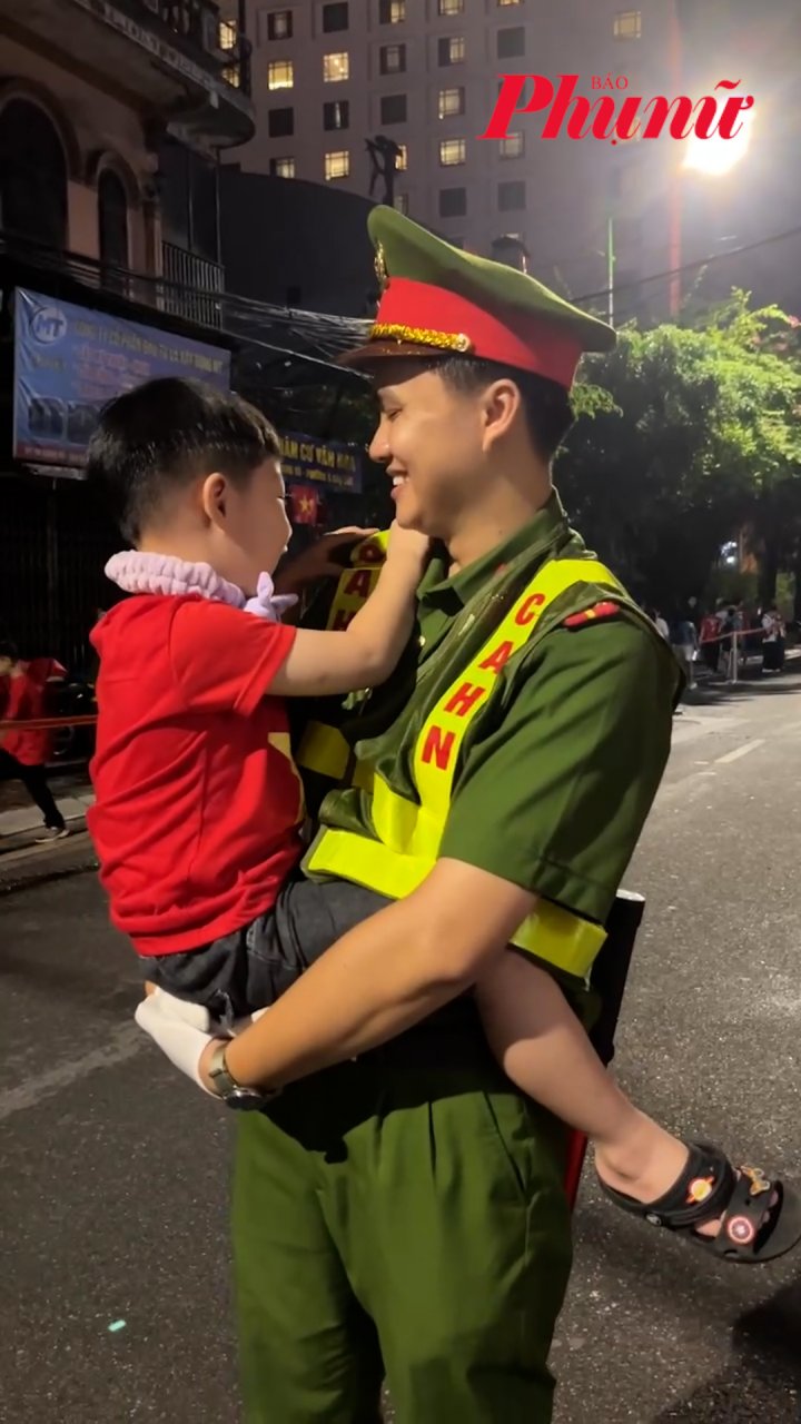 Chiến sĩ công an vừa bế vừa dạy bé trai hát “Như có Bác trong ngày đại thắng”